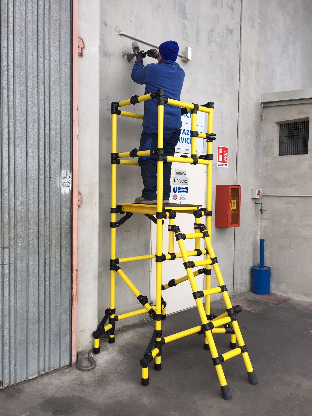 A man is working on a wall on a yellow ladder
