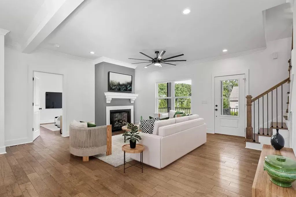 Spacious living room with wood floors, white walls, a sofa, fireplace, and a view to the outdoors.