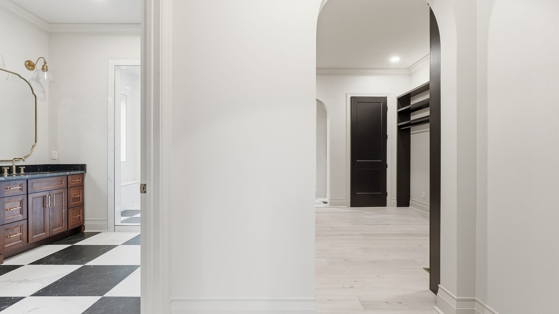 View of a bathroom entrance with black and white checkered floor, arched doorway leading to a walk-in closet.