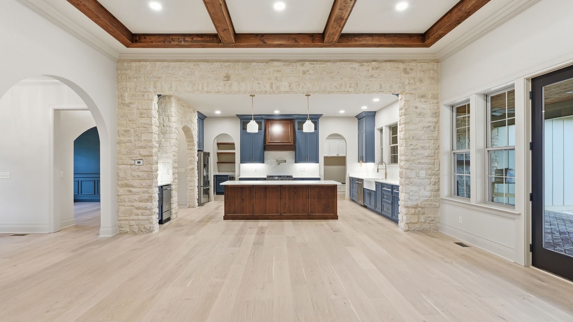 Spacious kitchen with a wooden floor, blue cabinets, and stone accents.