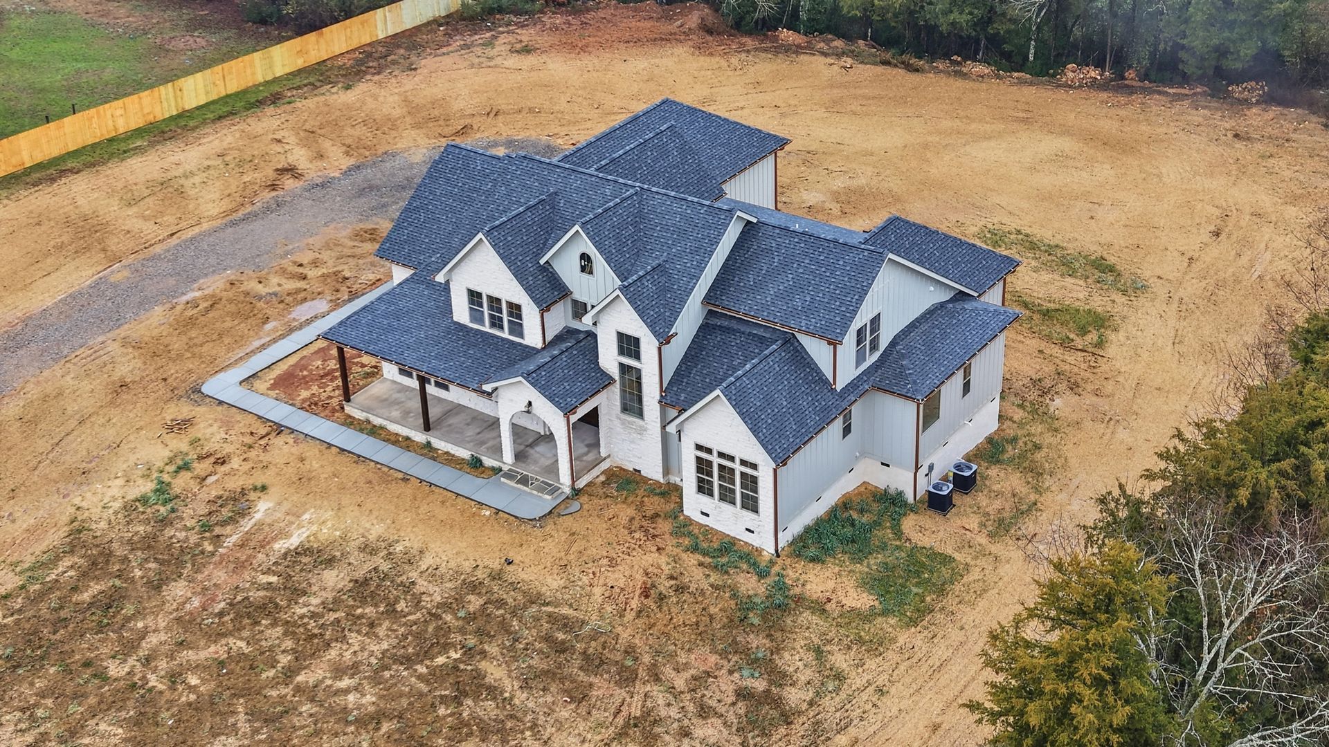 A house with a green siding and a black roof is for sale.