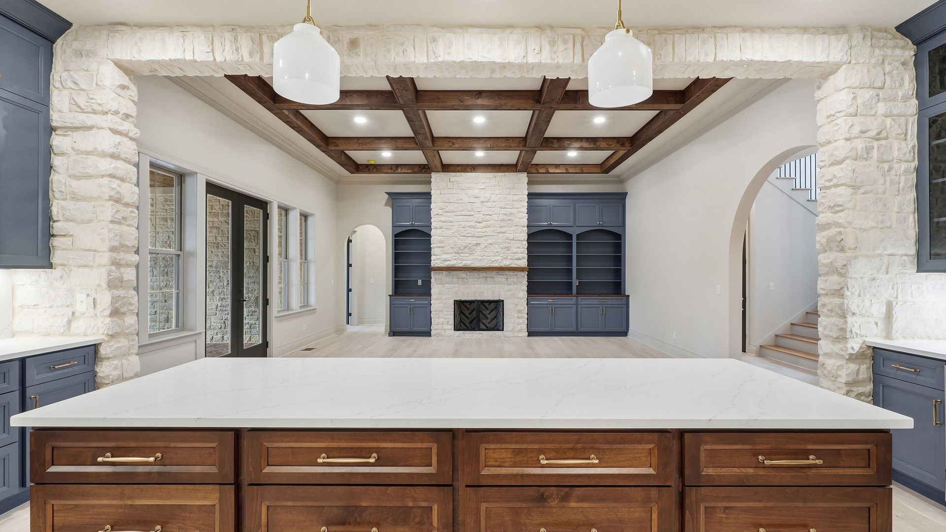 Kitchen with large island, stone accents, dark cabinets, and wood-beam ceiling.