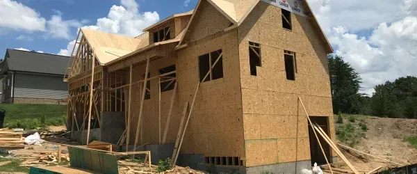 A large wooden house is being built in a rural area.