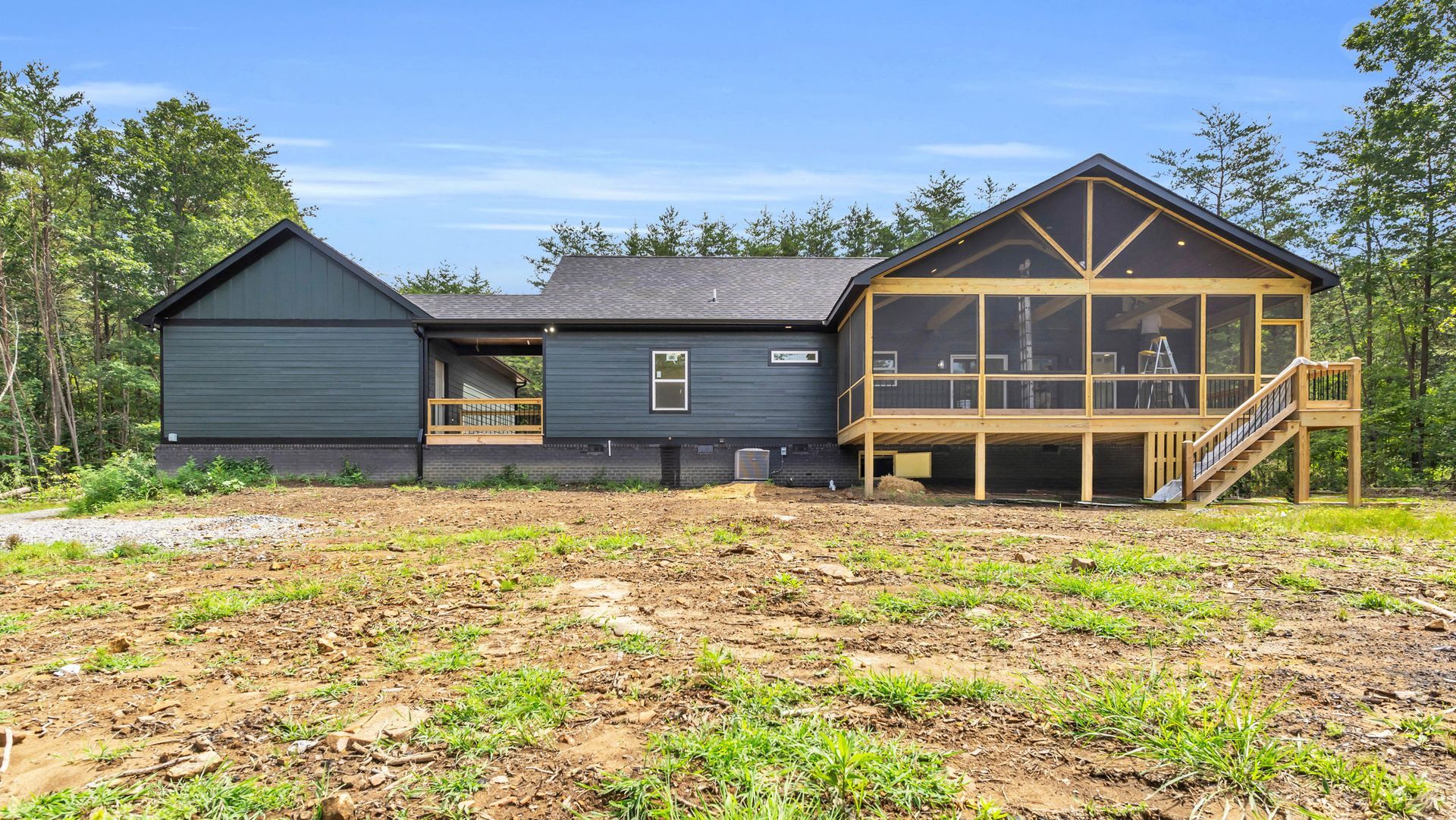 Blue house with screened porch and wooden deck under construction.