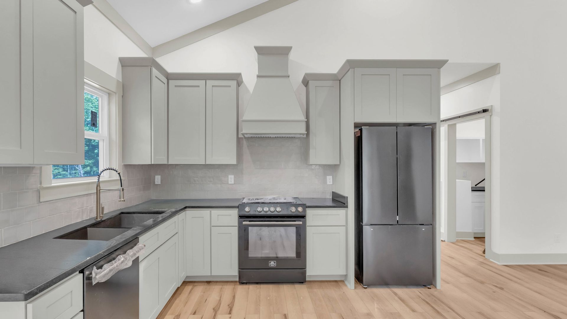 Gray kitchen with cabinets, appliances, and wooden floor.