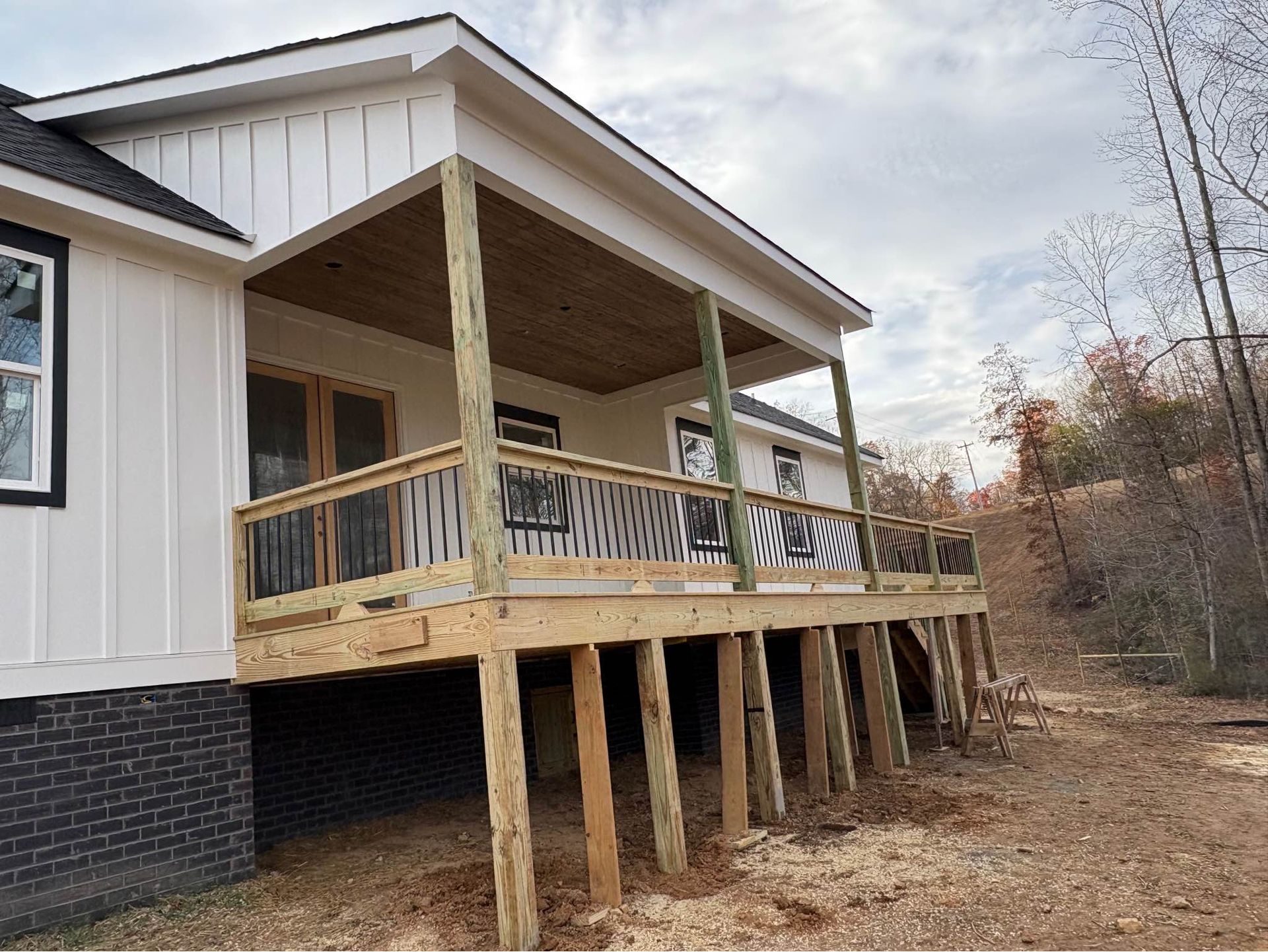 A white house with a wooden deck in front of it.