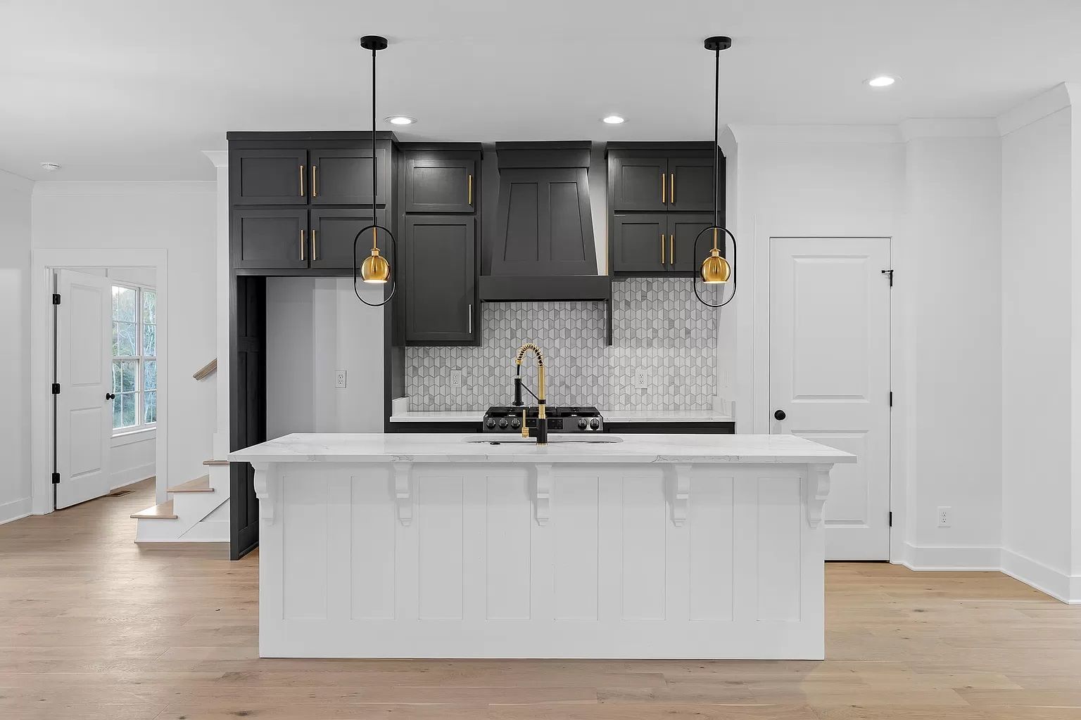 A kitchen with black cabinets and white counter tops and a large island.