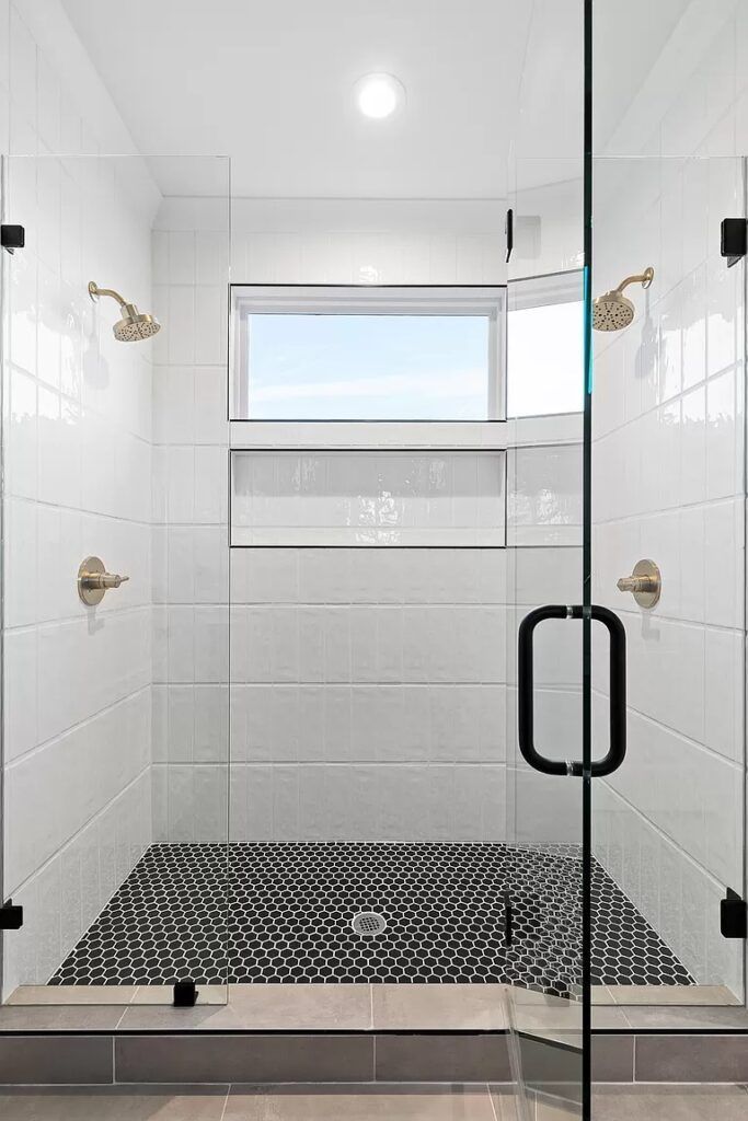 A bathroom with a walk in shower and a window.
