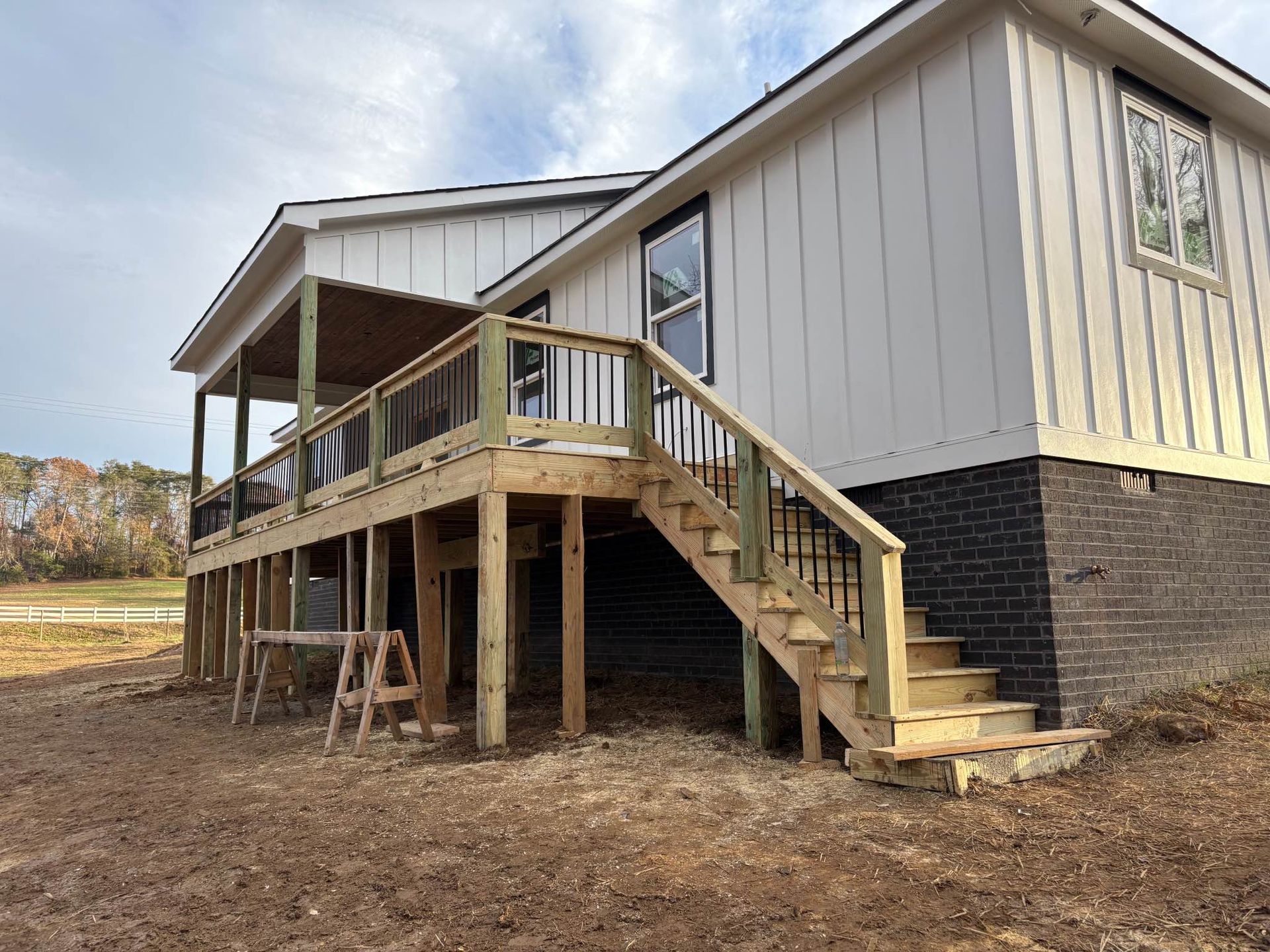 A mobile home with a wooden deck and stairs.