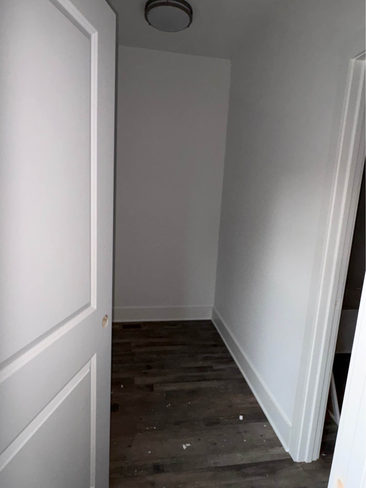A hallway with hardwood floors and white walls in a house.