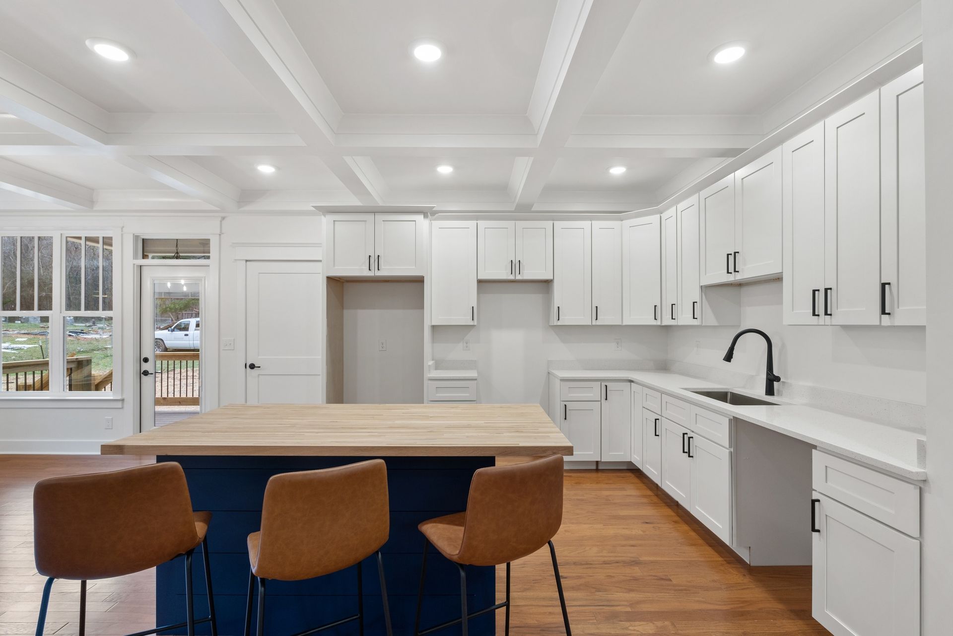 A kitchen with white cabinets and a blue island.