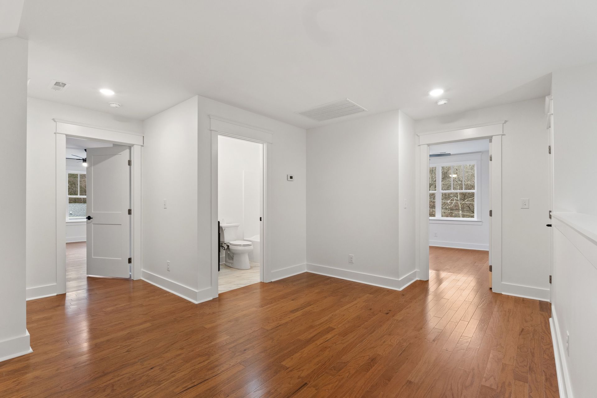 An empty living room with hardwood floors and white walls.