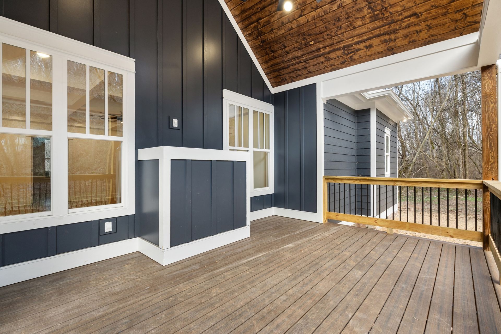 An empty porch with a wooden deck and a wooden ceiling.