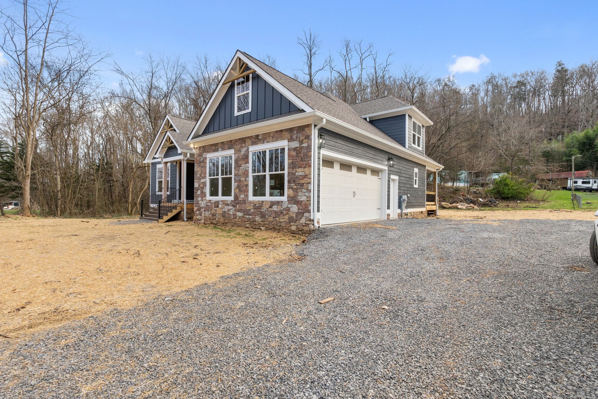 A house with a garage and a gravel driveway in front of it.