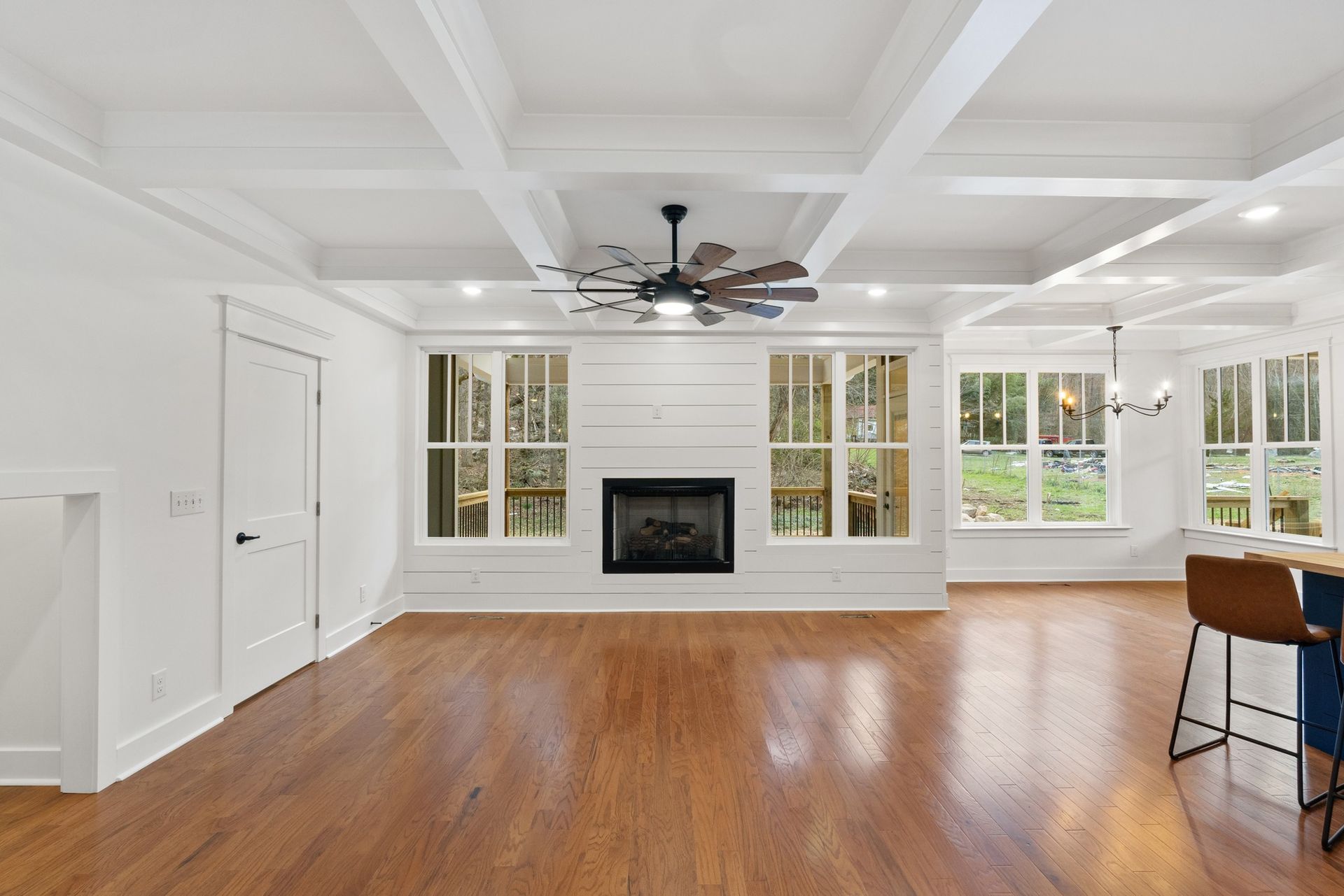 A living room with hardwood floors , a fireplace and a ceiling fan.