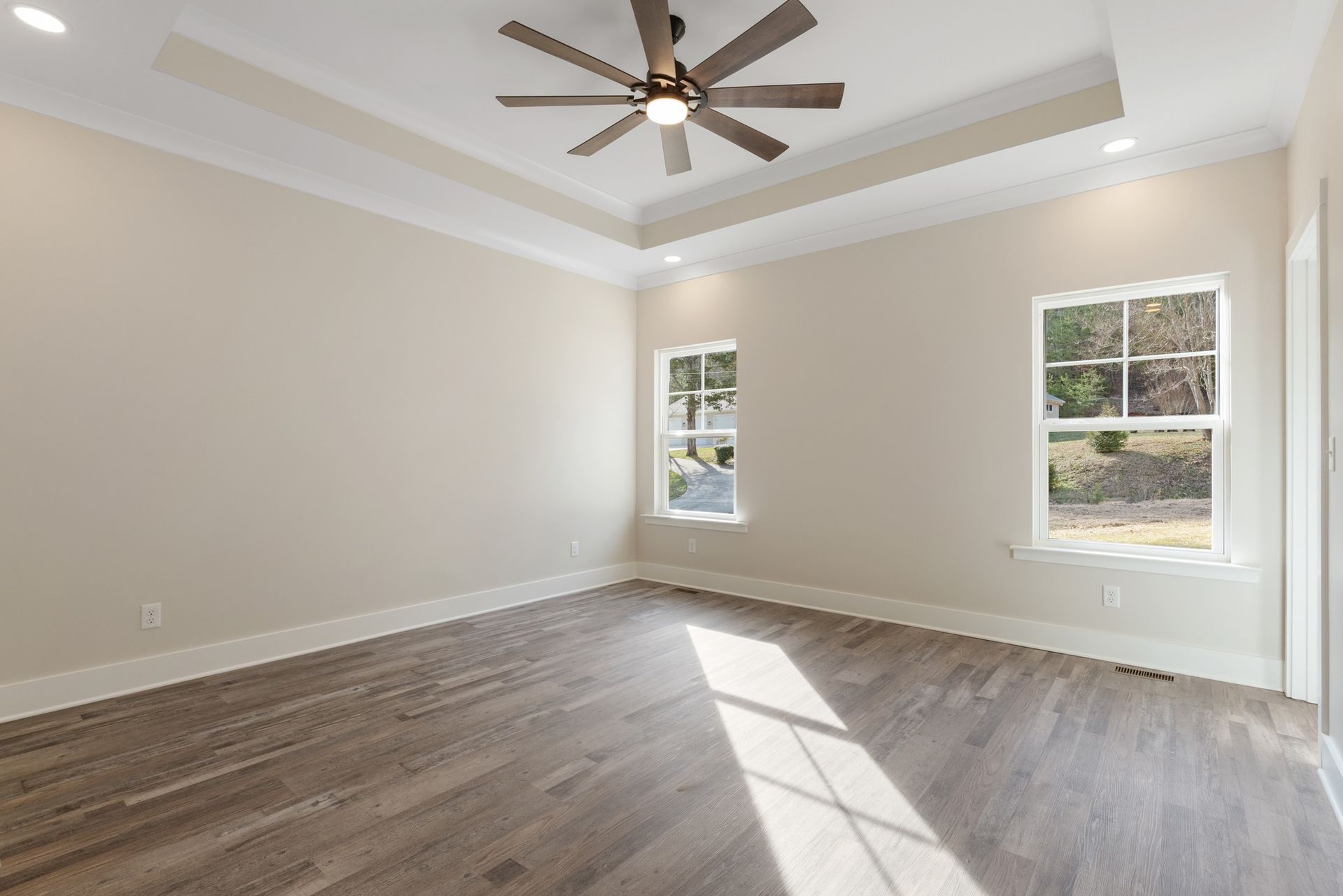 An empty room with hardwood floors and a ceiling fan.