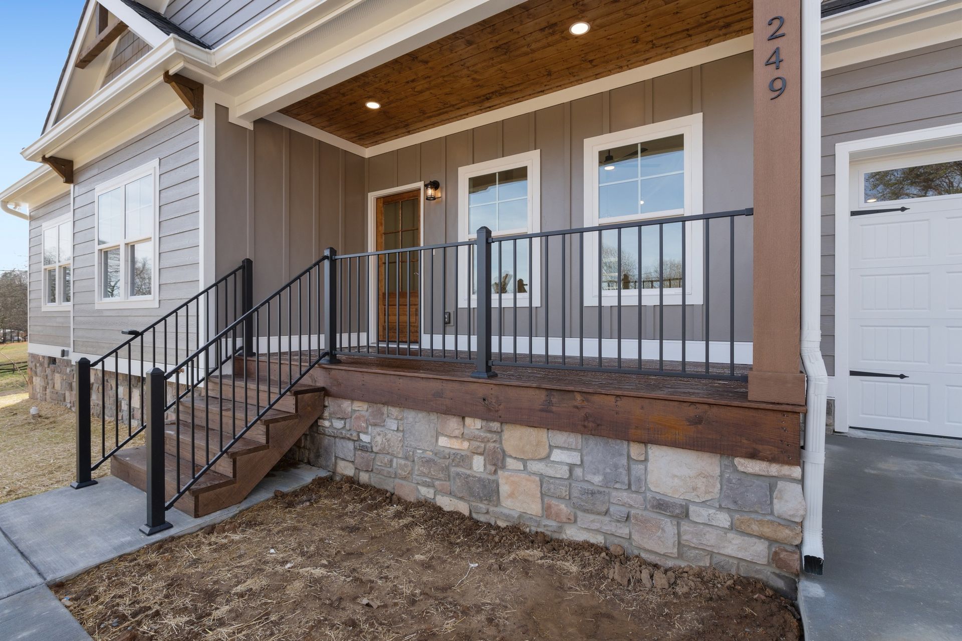 The front porch of a house with stairs and a wrought iron railing.
