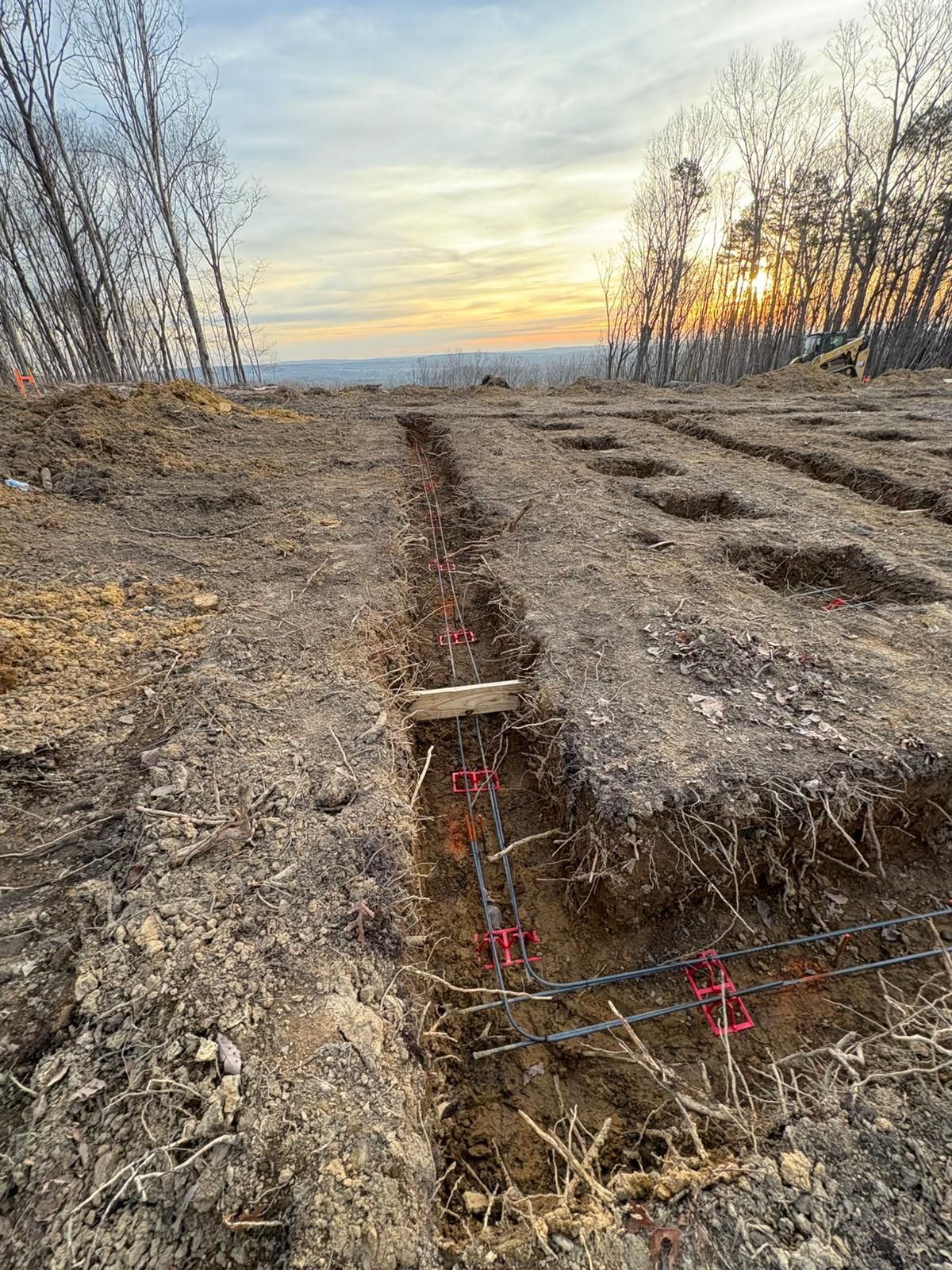 A dirt road with trees in the background and a sunset in the background.