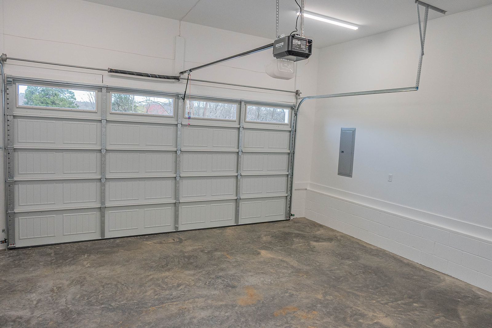 An empty garage with a garage door open and a garage door opener.