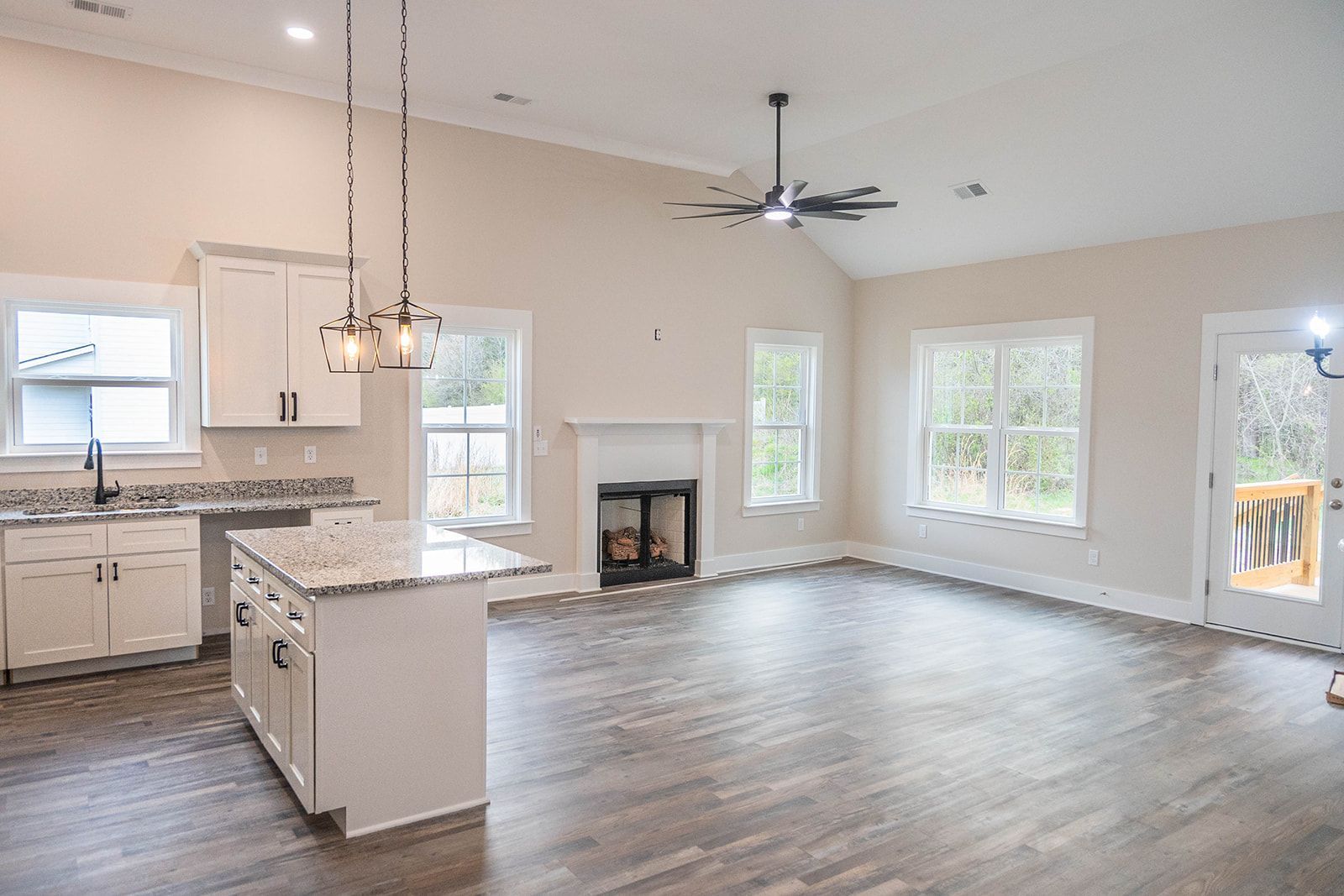 A kitchen and living room in a house with hardwood floors and white cabinets.