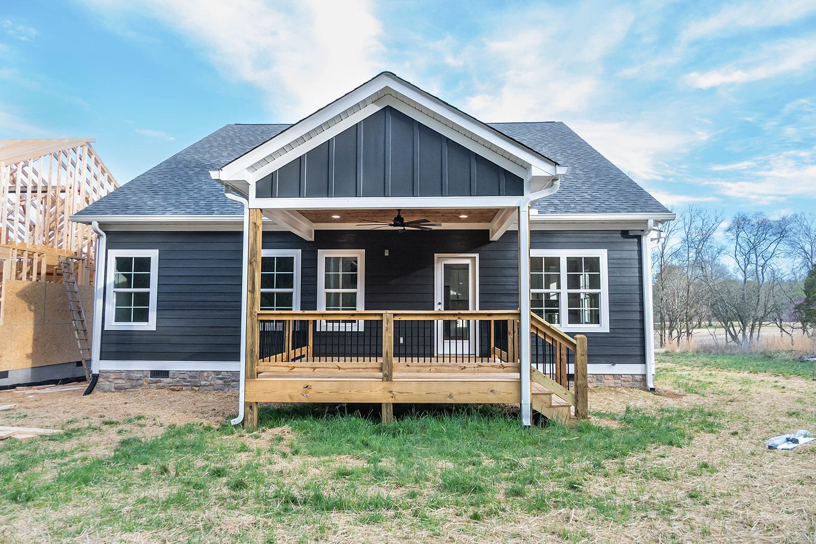 The front of a small house with a porch and a wooden deck.