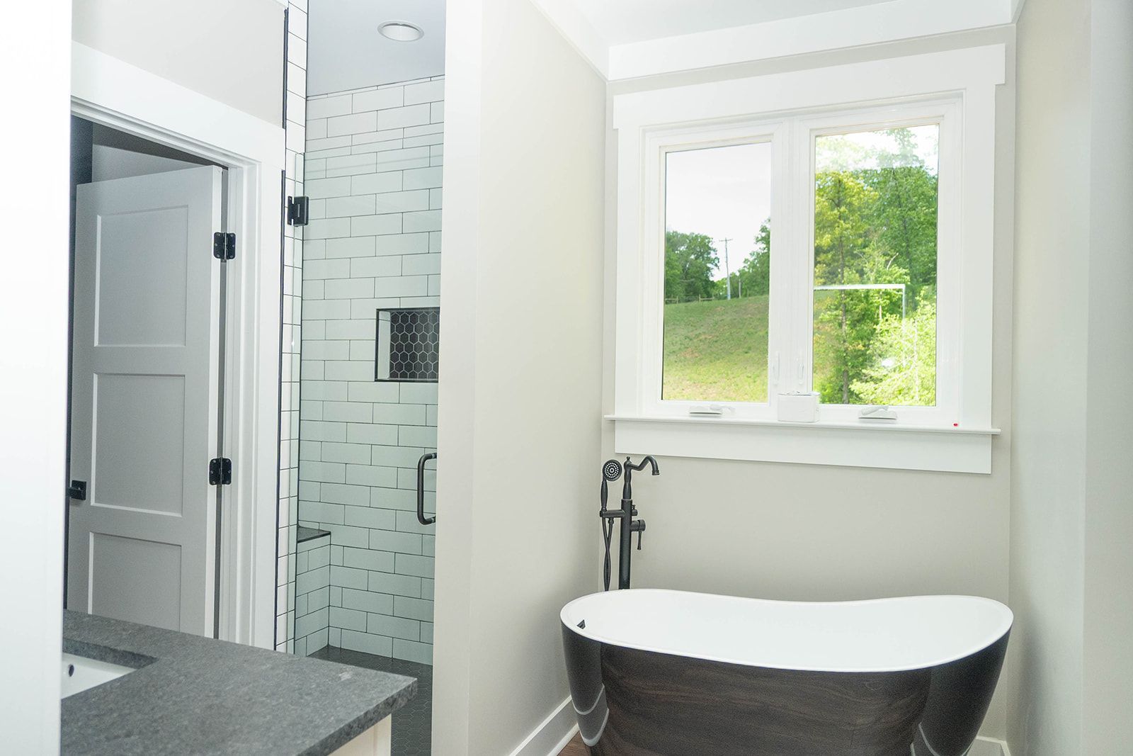 A bathroom with a tub , sink , shower and window.