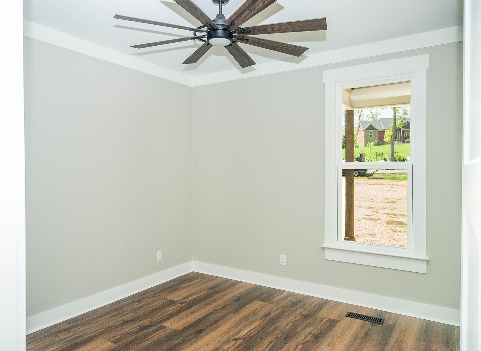 An empty room with a ceiling fan and a window.
