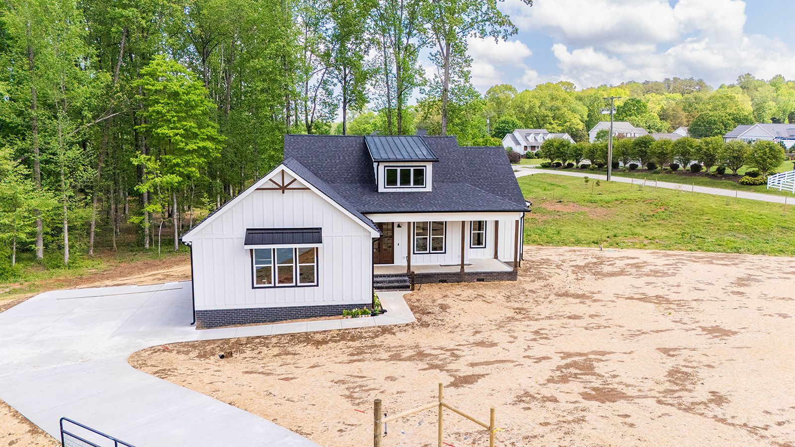 A white house with a blue roof is sitting on top of a dirt field.