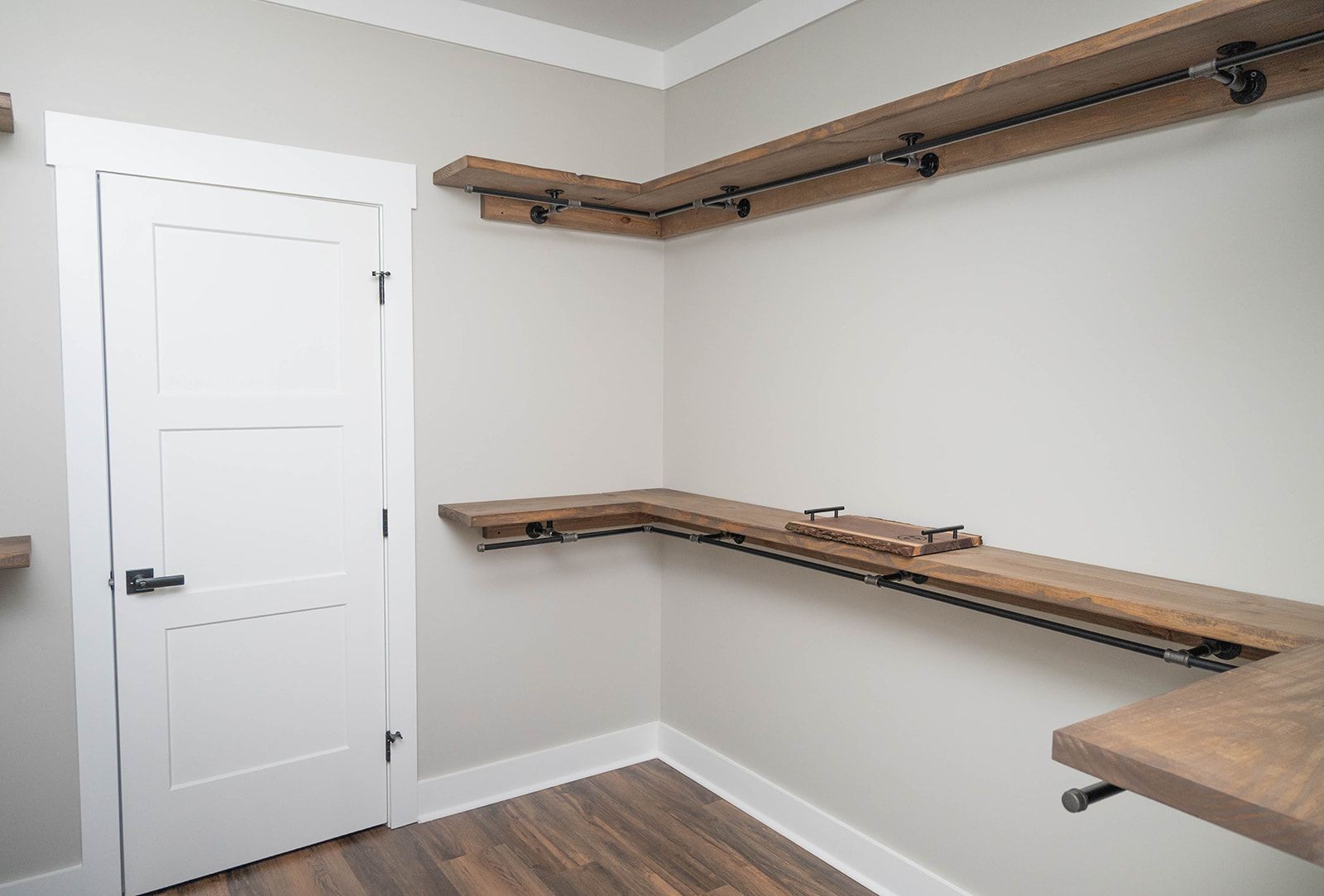 A walk in closet with wooden shelves and a door.