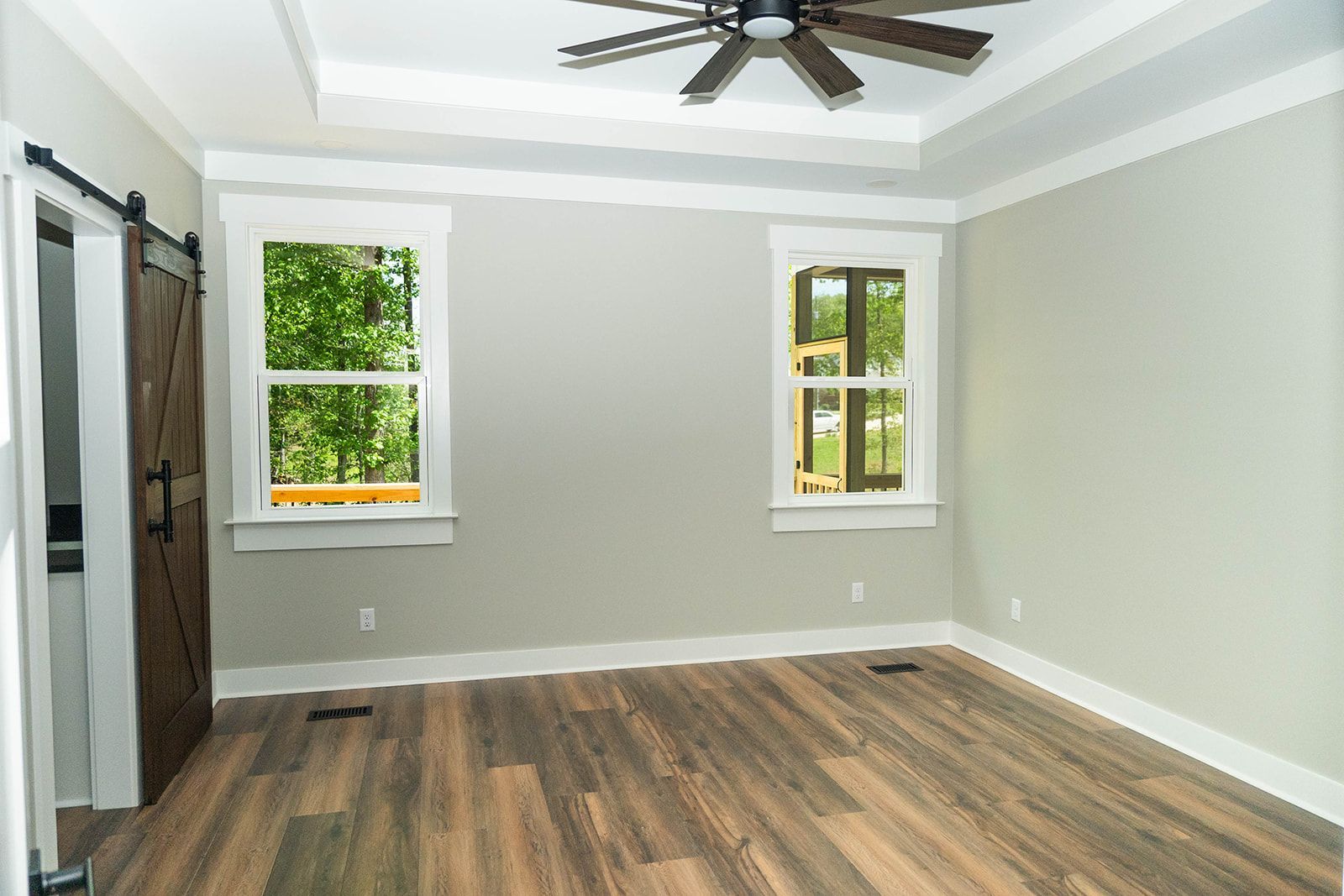 An empty room with hardwood floors and a ceiling fan.