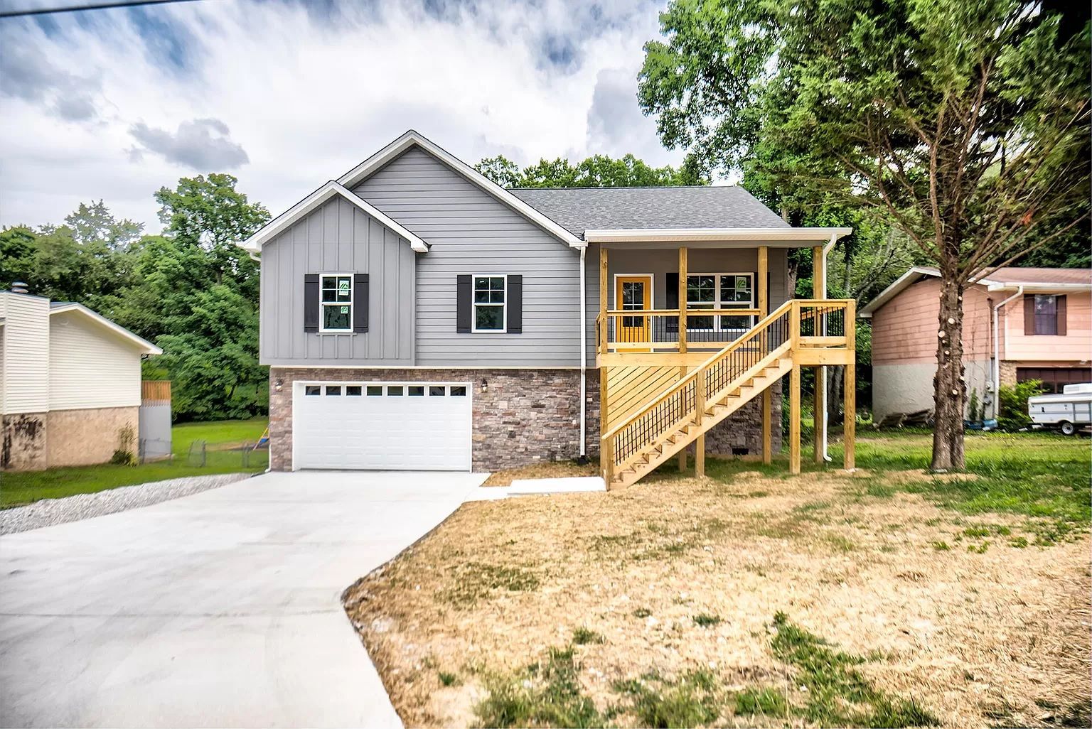 Covered patio with stone fireplace, seating area, and surrounding greenery.