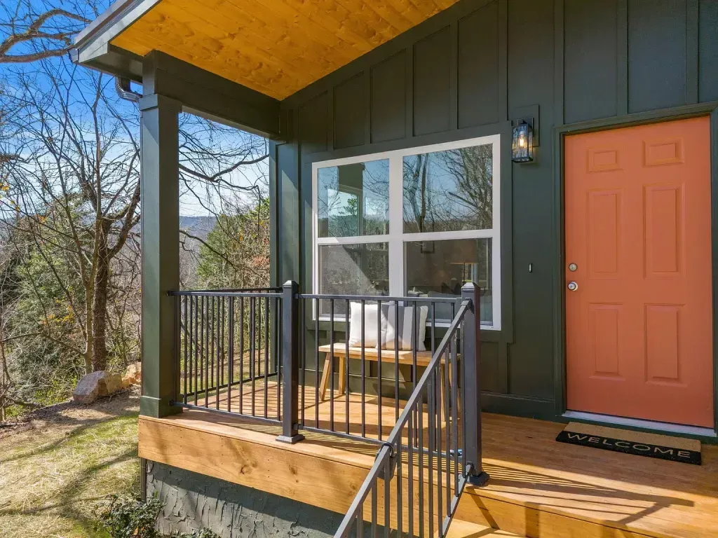 A small house with a porch and a red door.
