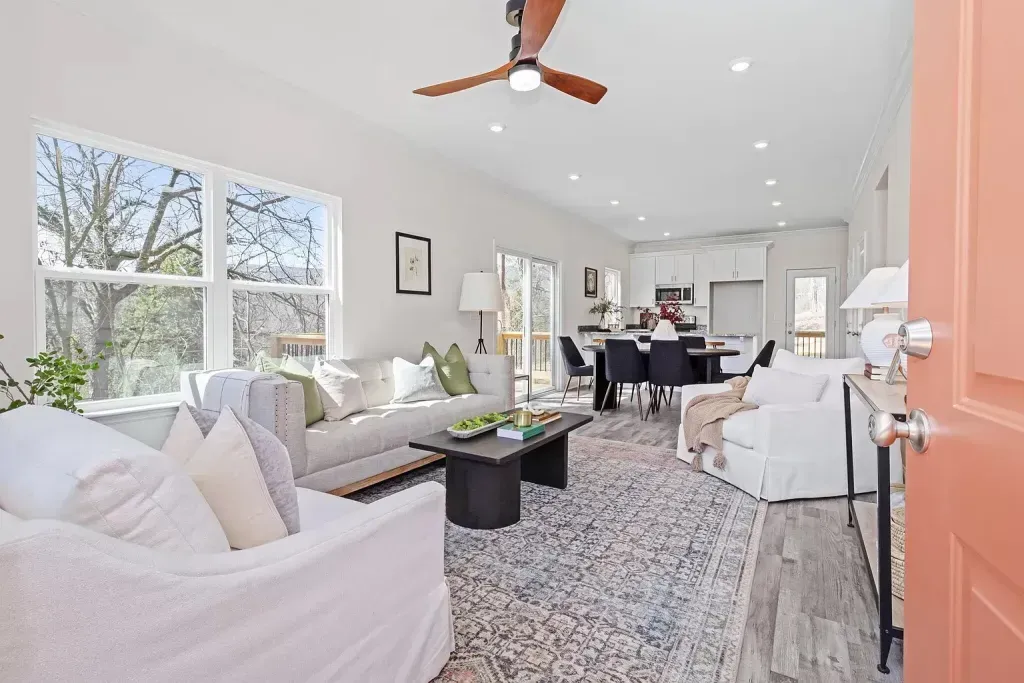A living room with a couch , chair , table and ceiling fan.