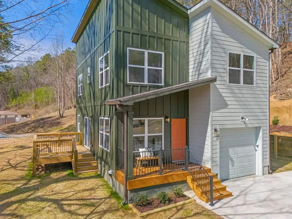 A green and white house with a garage and a porch.