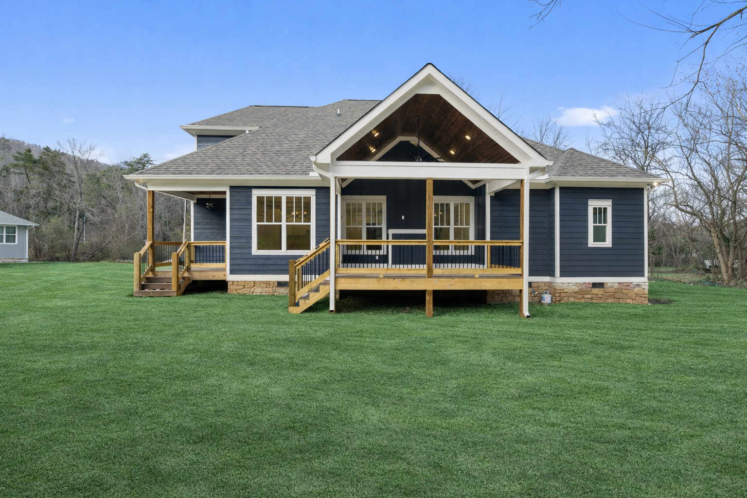 A large house with a large porch is sitting in the middle of a dirt field.