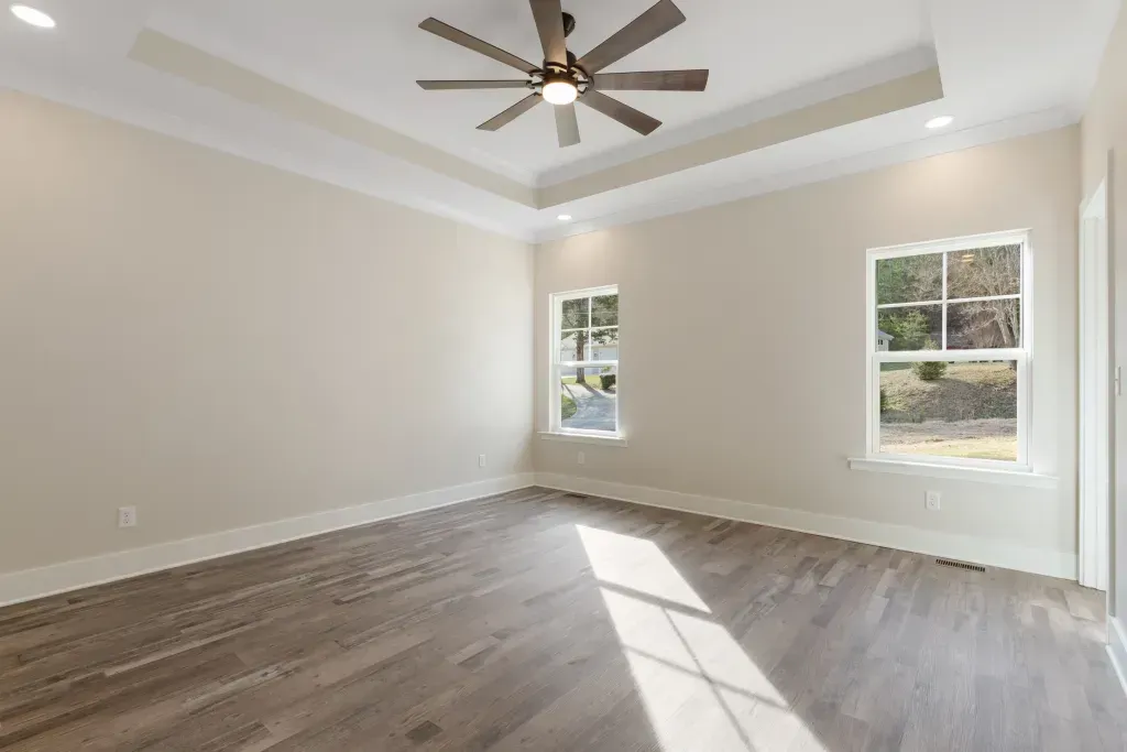 An empty room with hardwood floors and a ceiling fan.