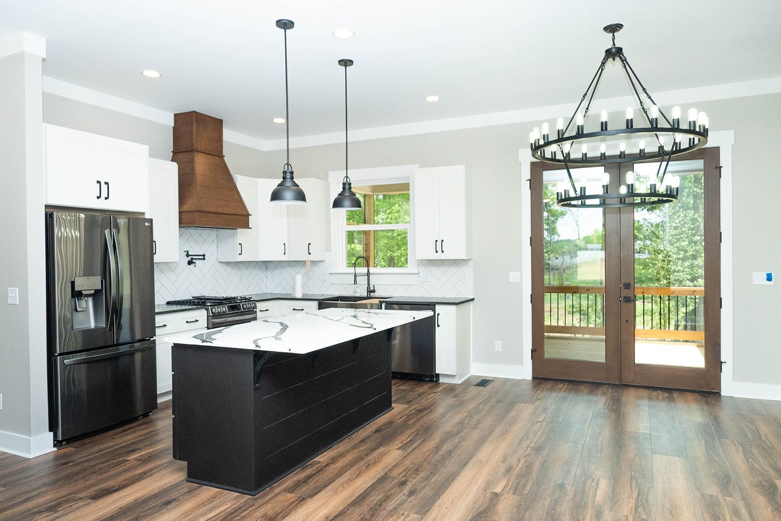 Modern kitchen with white cabinets, black island, and doors to a deck.