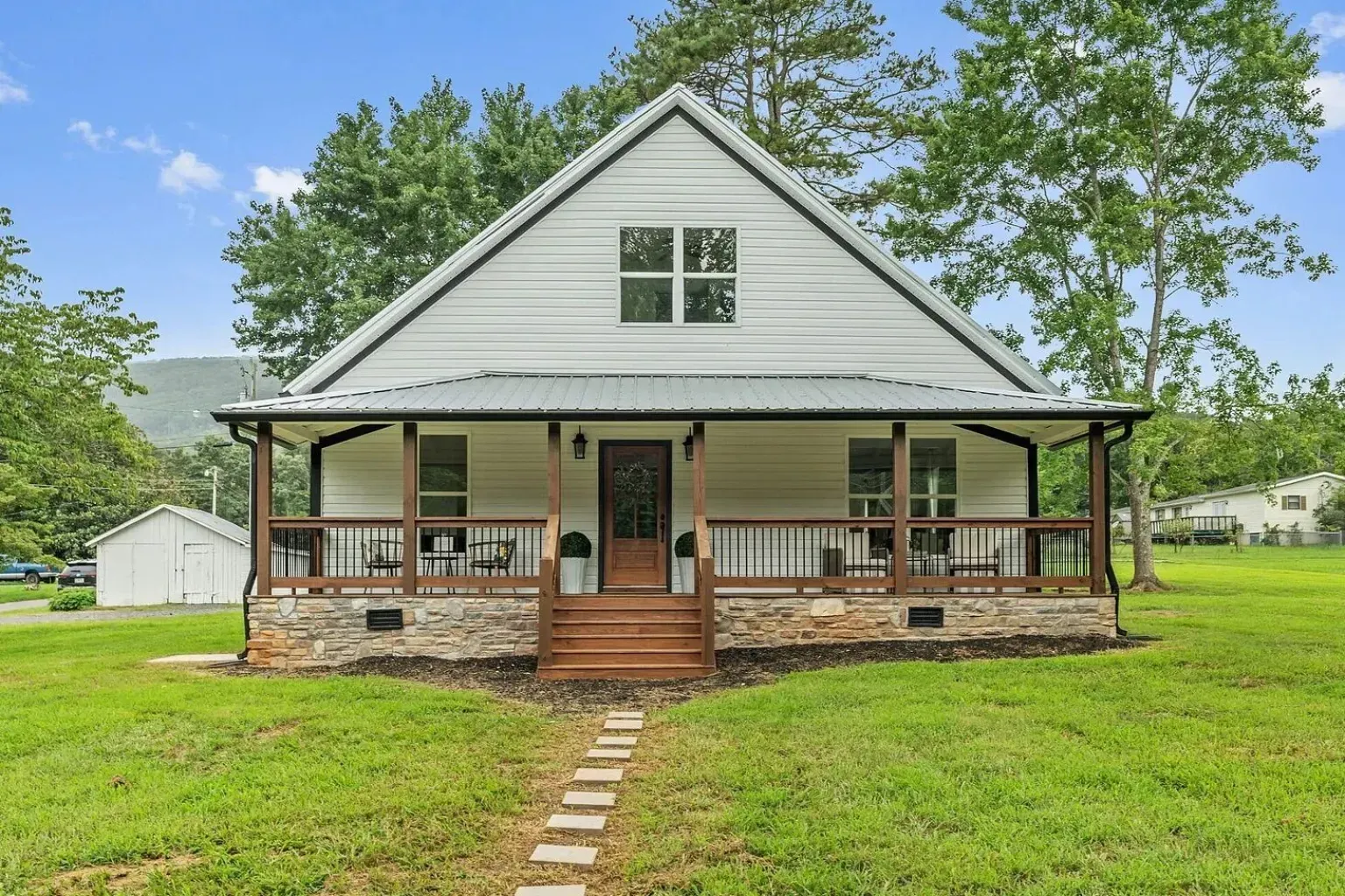 A white house with a porch and a walkway leading to it.