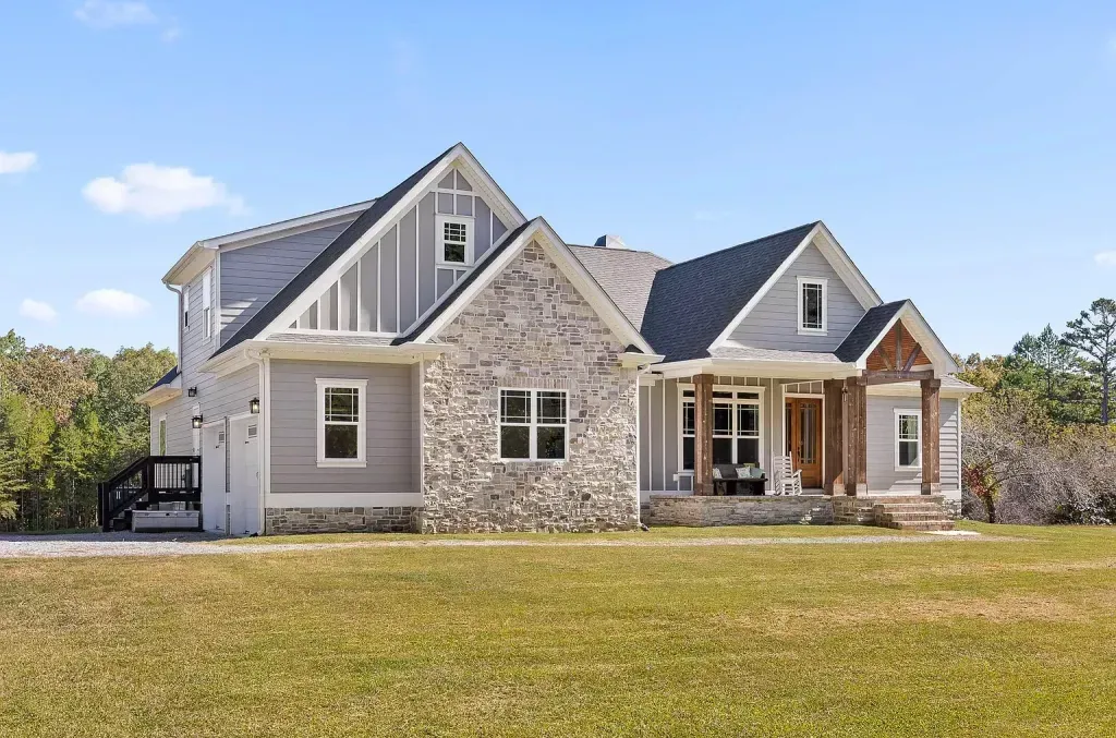 A large house is sitting on top of a lush green field.