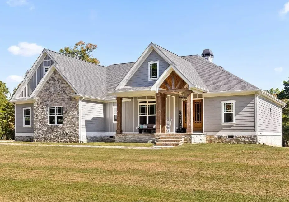 A large house with a gray roof is sitting on top of a lush green field.