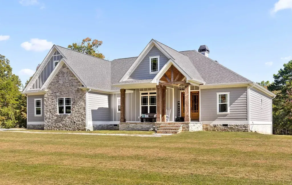 A large house is sitting on top of a lush green field.