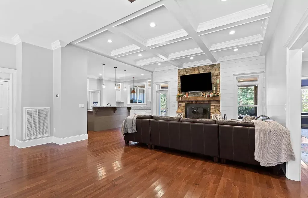 A living room with hardwood floors , a couch , a fireplace and a flat screen tv.