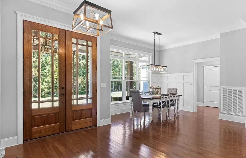 A living room with hardwood floors and a dining room with a table and chairs.
