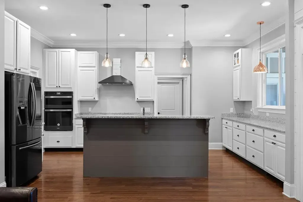 A kitchen with white cabinets , black appliances , and a large island.