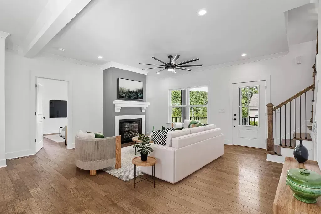 Spacious living room with wood floors, fireplace, white sofa, and an open doorway.
