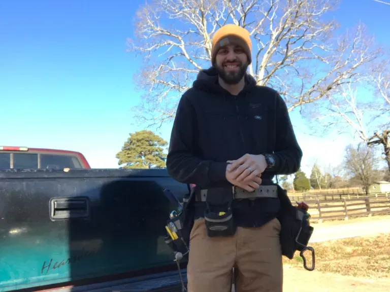 A man with a beard is standing in front of a truck.
