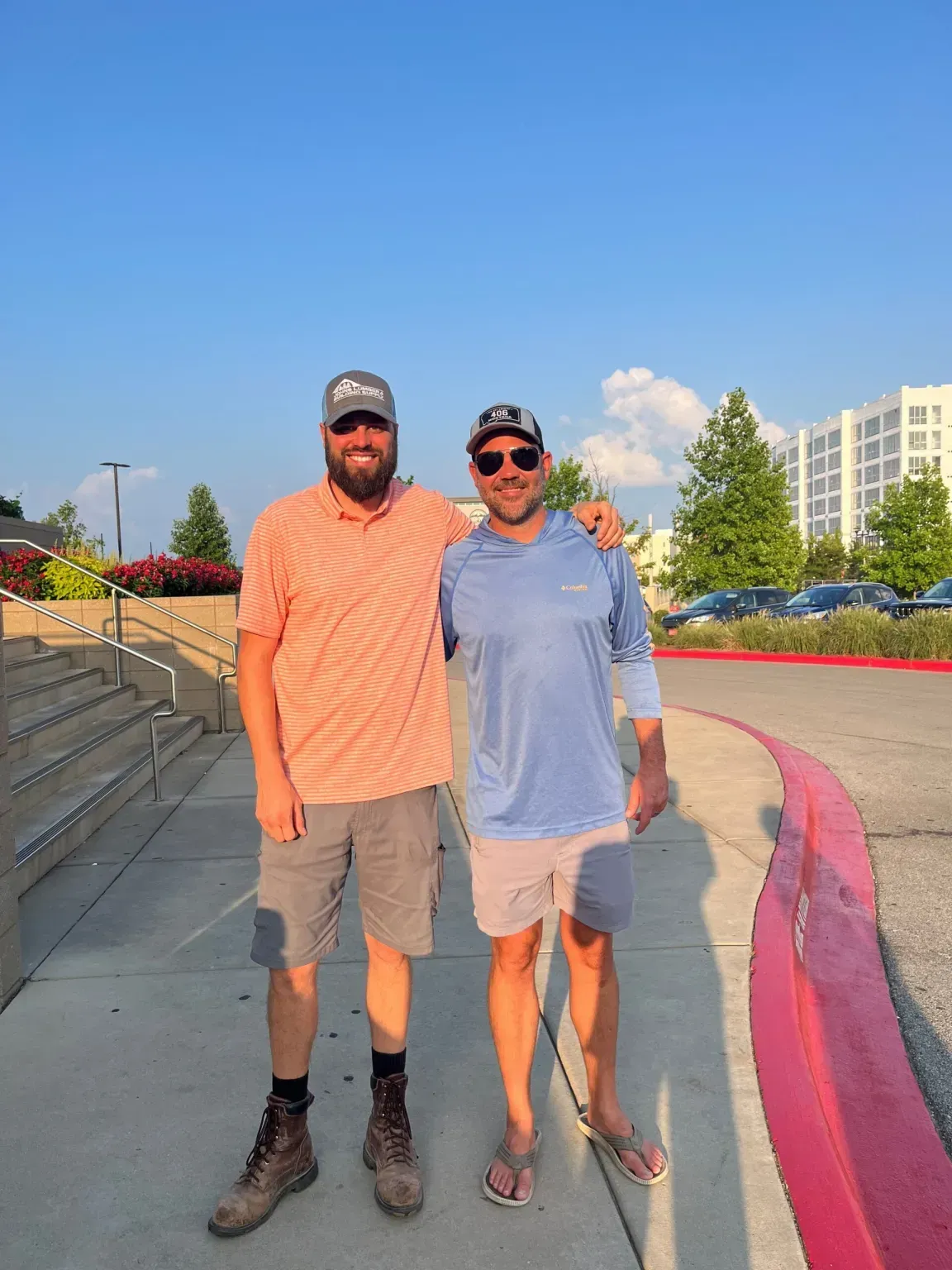 Two men are standing next to each other on a sidewalk.