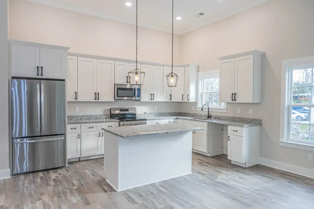 A kitchen with white cabinets , stainless steel appliances , and a large island.