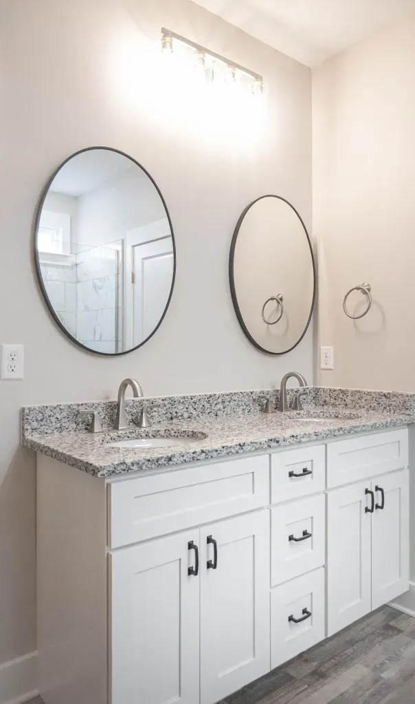 A bathroom with two sinks and two round mirrors.