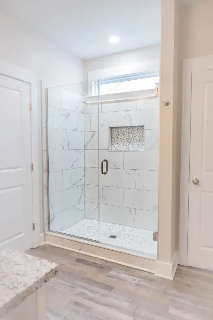 A bathroom with a walk in shower and a window.